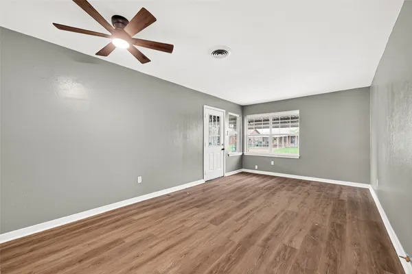 an empty room with wooden floor and windows