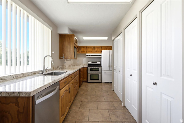 7050 South 260 East Midvale, UT 84047 - Photo 10 of 28 Galley kitchen featuring light-toned wood cabinetry, granite countertops, and tile flooring