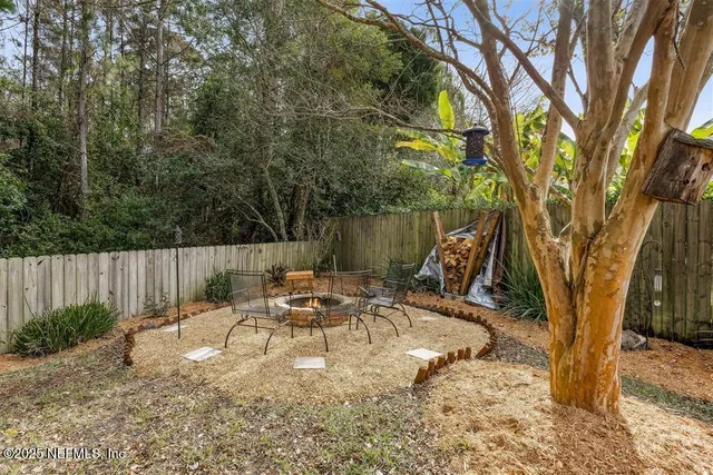 a view of backyard with a table and chairs and a large tree