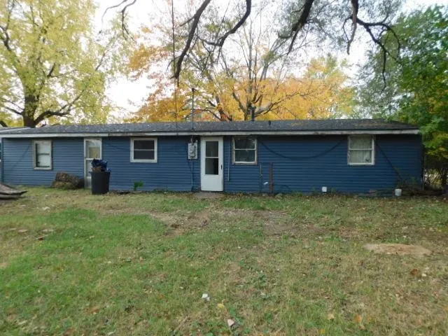 a brick house with a yard plants and large tree