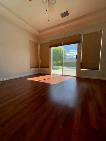 a view of an empty room with wooden floor and a window