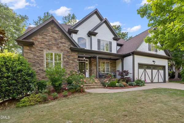 a front view of a house with lots of trees and plants