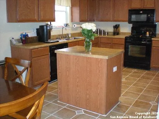 a kitchen with granite countertop a stove a sink a refrigerator and cabinets