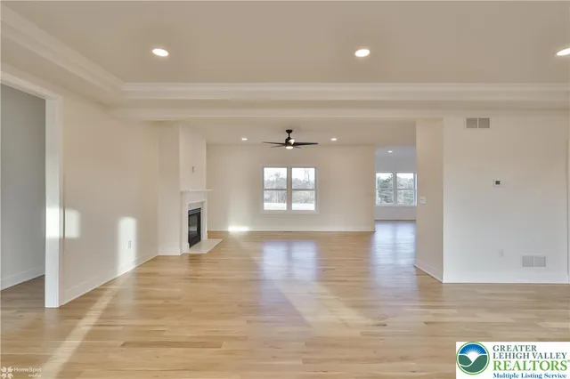 a view of an empty room with wooden floor fireplace and a window