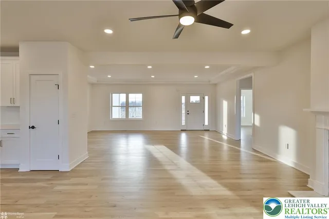 a large kitchen with stainless steel appliances kitchen island a sink dishwasher a refrigerator and white cabinets with wooden floor