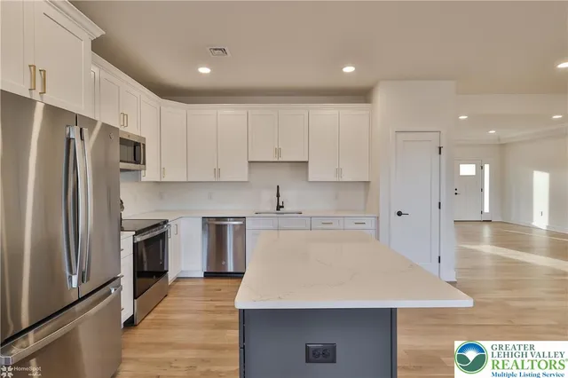 a kitchen with stainless steel appliances kitchen island granite countertop a refrigerator and a stove top oven