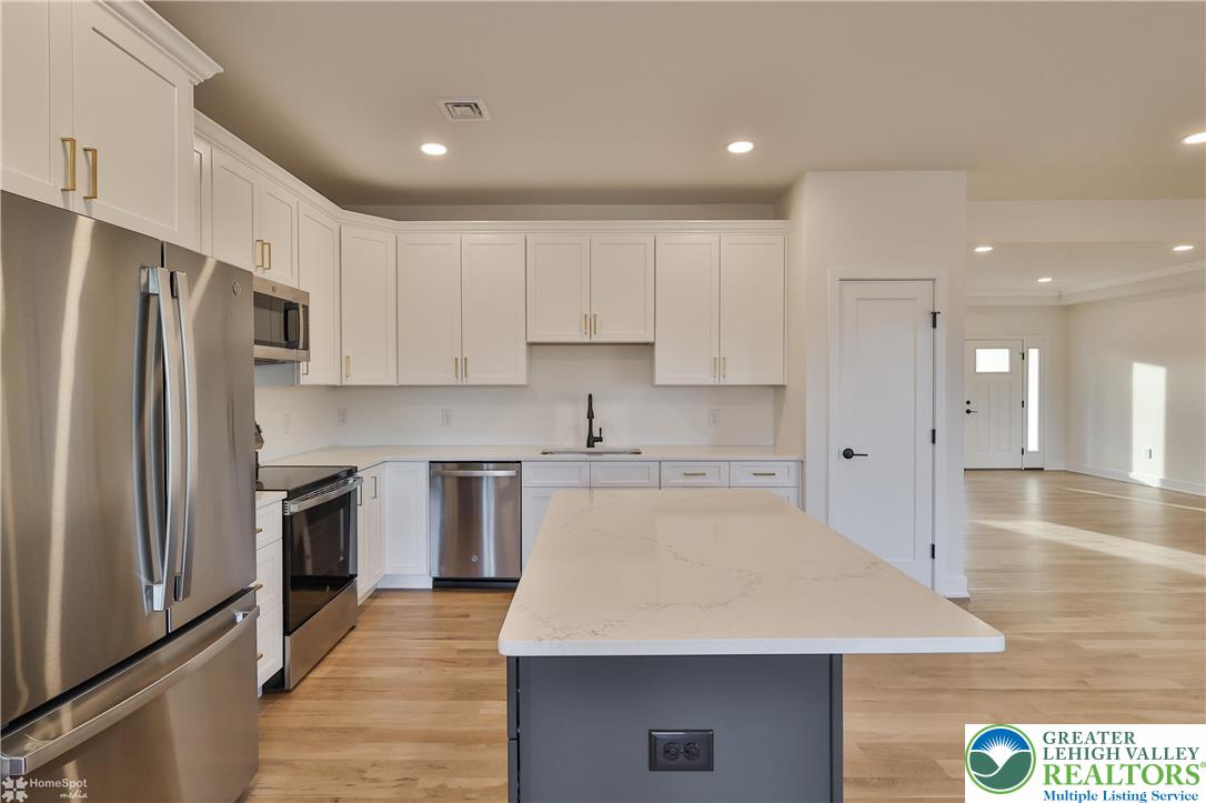 448 Long Lane Road Walnutport, PA 18088 - Photo 23 of 65 a large kitchen with stainless steel appliances kitchen island a sink dishwasher a refrigerator and white cabinets with wooden floor