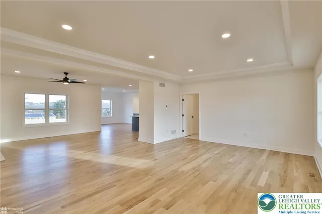 a view of empty room with wooden floor and fan