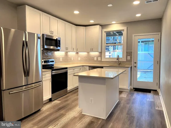 a kitchen with stainless steel appliances a refrigerator a sink a stove a microwave and wooden floor