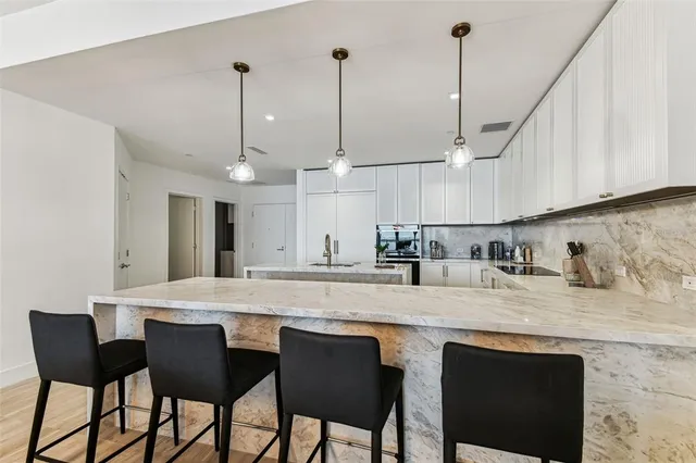 a kitchen with stainless steel appliances granite countertop a sink a stove a dining table and chairs