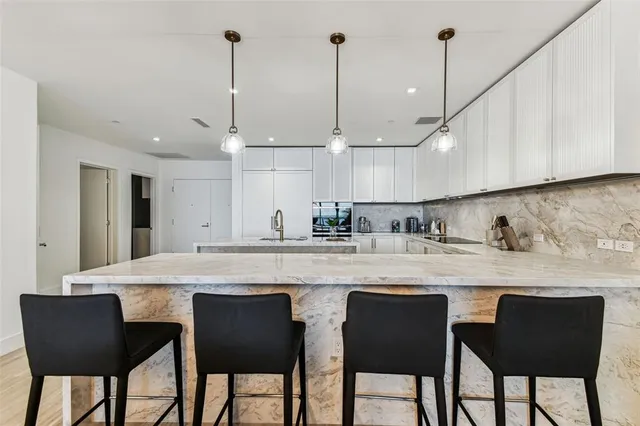 a kitchen with stainless steel appliances granite countertop a sink a stove a refrigerator and a wooden floor