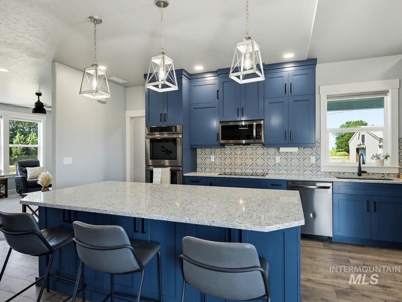 4950 West Columbia Road Nampa, ID 83687 - Photo 14 of 50 Kitchen featuring a spacious island with light-toned countertop, blue cabinetry, stainless steel appliances, and decorative tile backsplash
