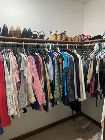 a view of walk in closet with clothes and shoes