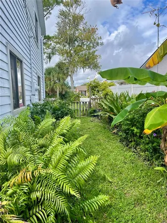a view of a yard with plants and a brick wall