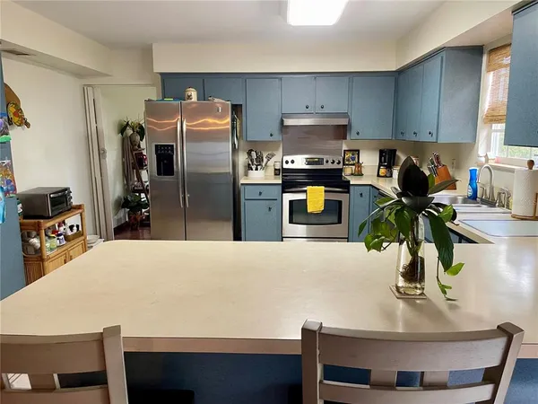 a kitchen with stainless steel appliances a dining table a refrigerator and a stove
