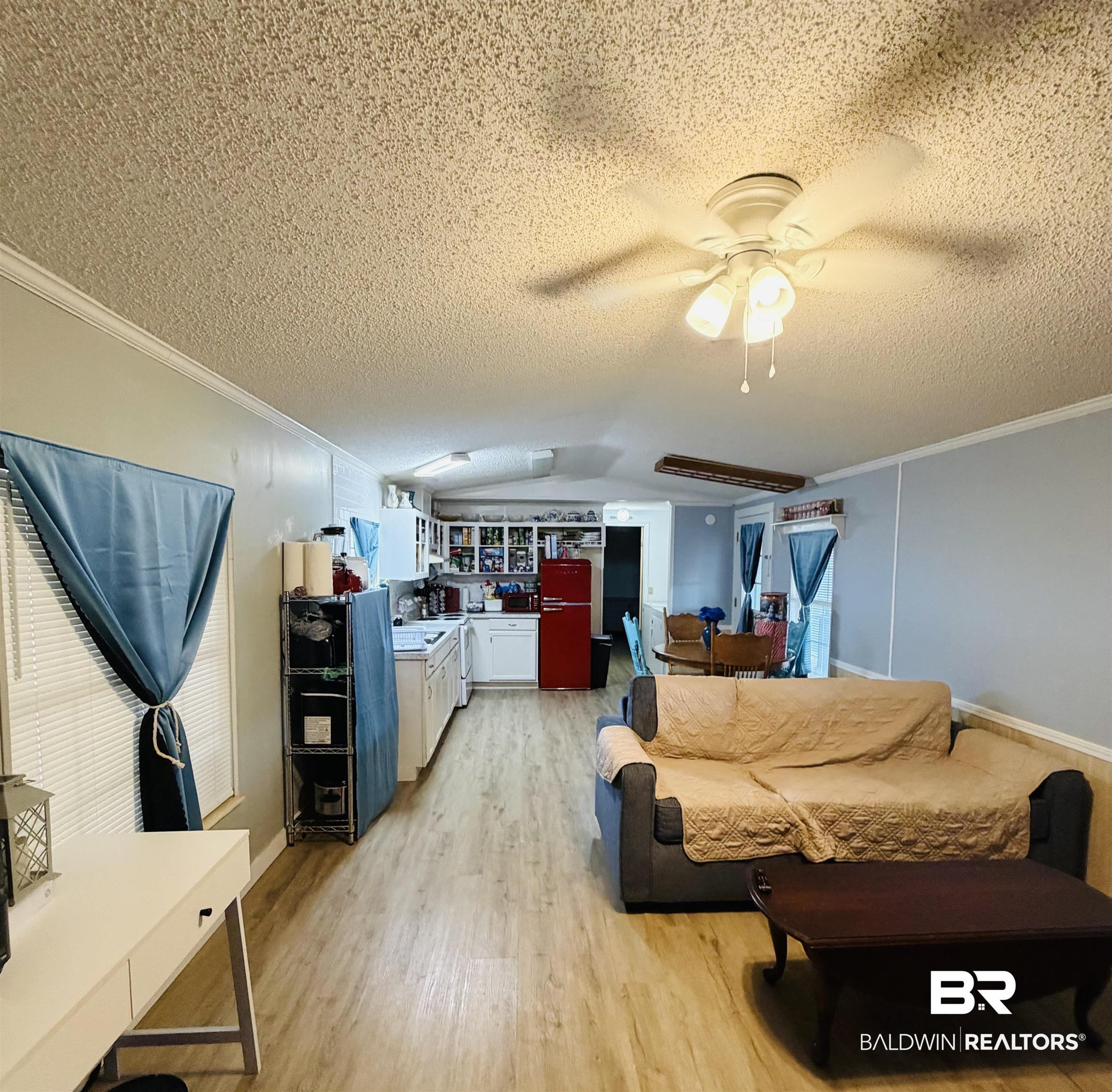 1913 Maria Lane Lillian, AL 36549 - Photo 6 of 35 Living area featuring light wood-type flooring, ornamental molding, a textured ceiling, a ceiling fan, and vaulted ceiling