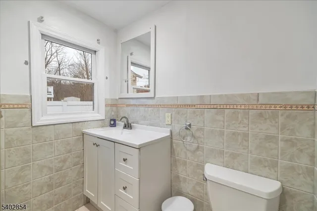 a bathroom with a toilet a sink a mirror a window and vanity