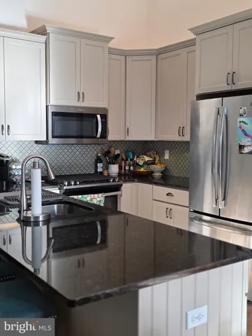 a kitchen with granite countertop a refrigerator a stove and a sink