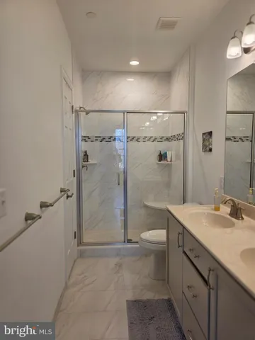 a bathroom with a shower sink vanity and toilet