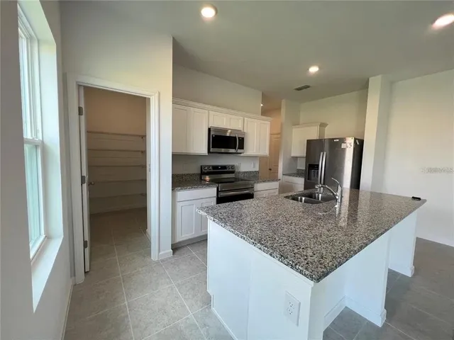a kitchen with kitchen island granite countertop a stove and a sink