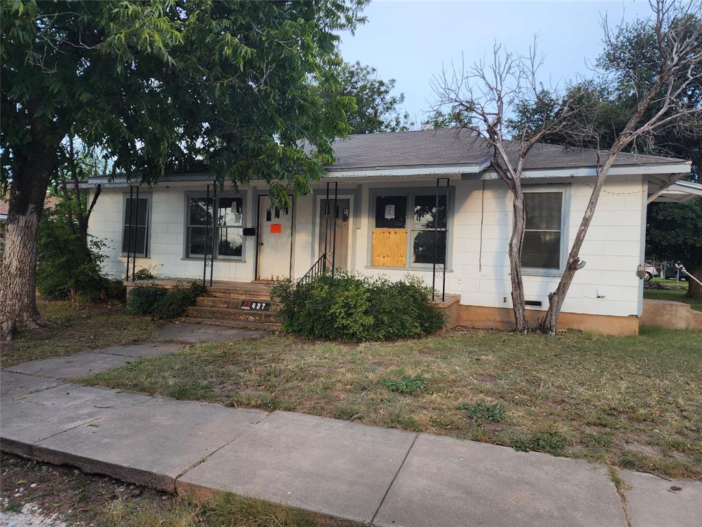 407 Largent Avenue Ballinger, TX 76821 - Photo 1 of 17 View of front facade with covered porch, roof with shingles, and a front lawn