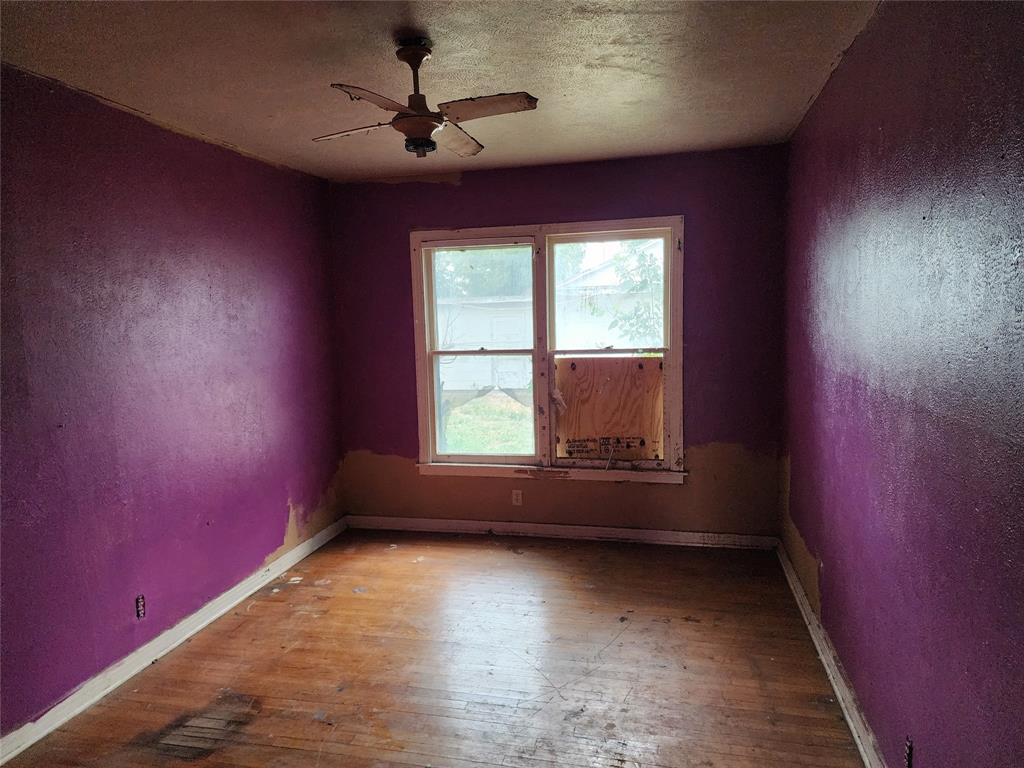 407 Largent Avenue Ballinger, TX 76821 - Photo 5 of 17 Spare room with a ceiling fan, hardwood / wood-style floors, a textured ceiling, and a textured wall
