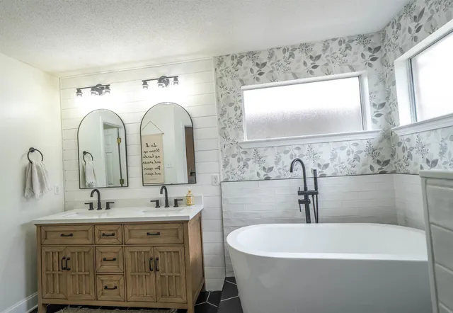 a spacious bathroom with a double vanity sink mirror and bathtub