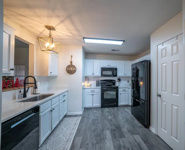 a kitchen with stainless steel appliances a sink cabinets and wooden floor