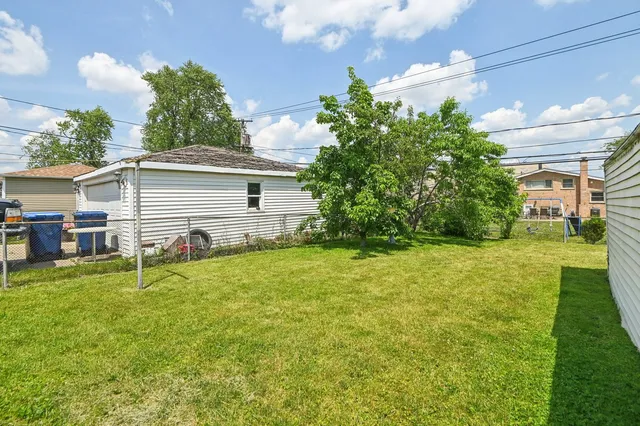 a backyard of a house with table and chairs plants and large tree