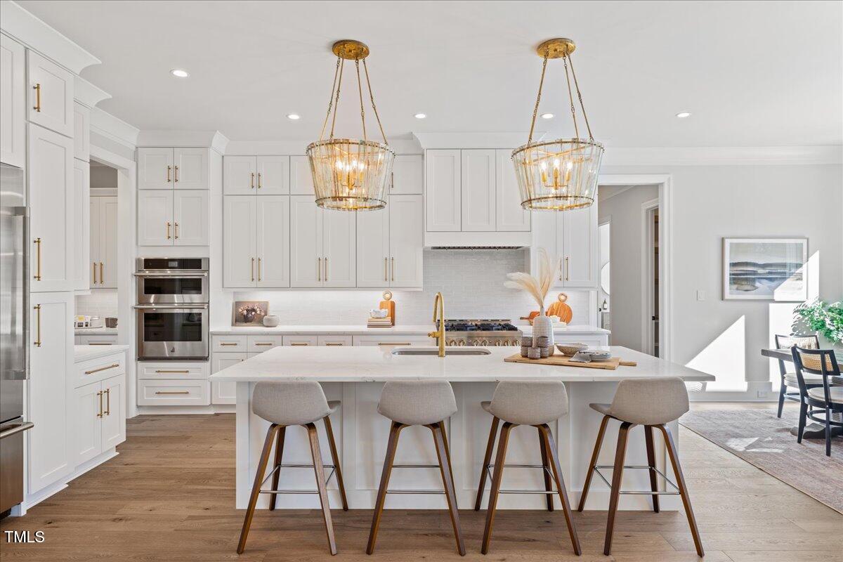 4906 Tremont Drive Raleigh, NC 27609 - Photo 13 of 78 a kitchen with stainless steel appliances kitchen island granite countertop a dining table chairs and white cabinets