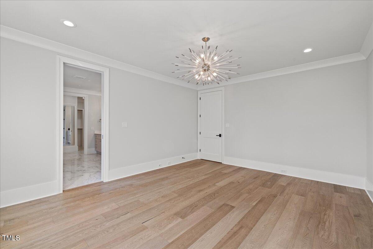 4906 Tremont Drive Raleigh, NC 27609 - Photo 44 of 78 an empty room with wooden floor and chandelier