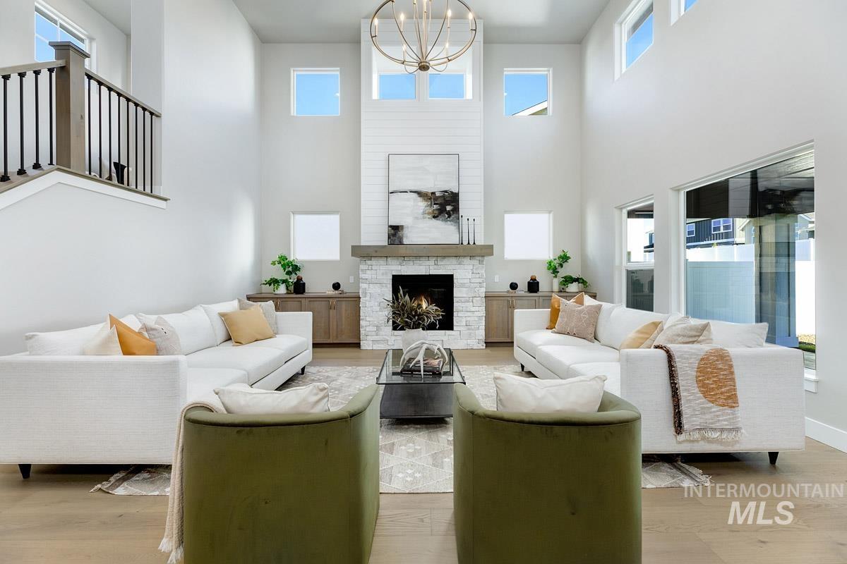 6792 Saddle Bred Way Star, ID 83669 - Photo 2 of 33 Living area with healthy amount of natural light, a stone fireplace, wood finished floors, and a towering ceiling