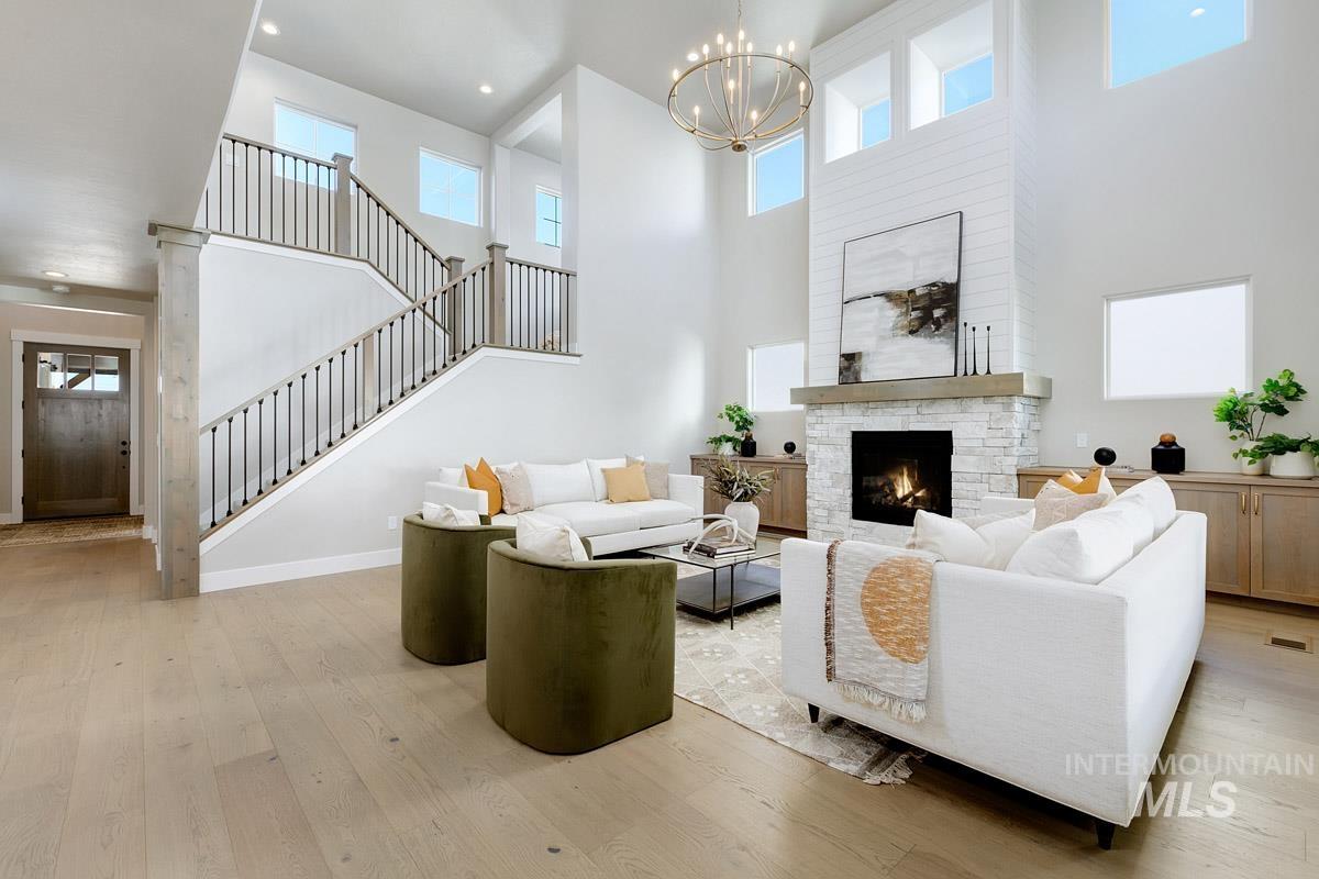 6792 Saddle Bred Way Star, ID 83669 - Photo 3 of 33 Living area with a high ceiling, stairway, wood-type flooring, a stone fireplace, and a chandelier