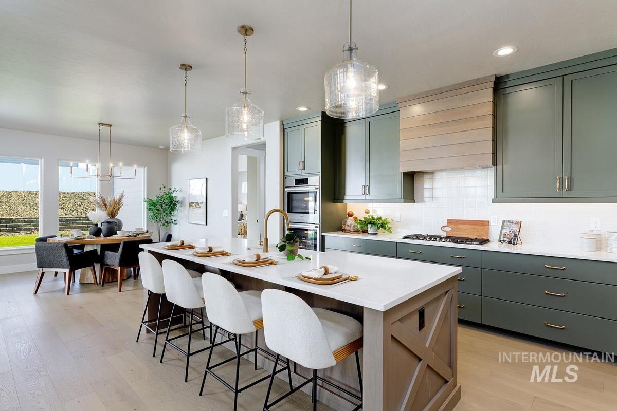 6792 Saddle Bred Way Star, ID 83669 - Photo 7 of 33 Kitchen featuring pendant lighting, backsplash, light wood finished floors, a kitchen bar, and a kitchen island with sink