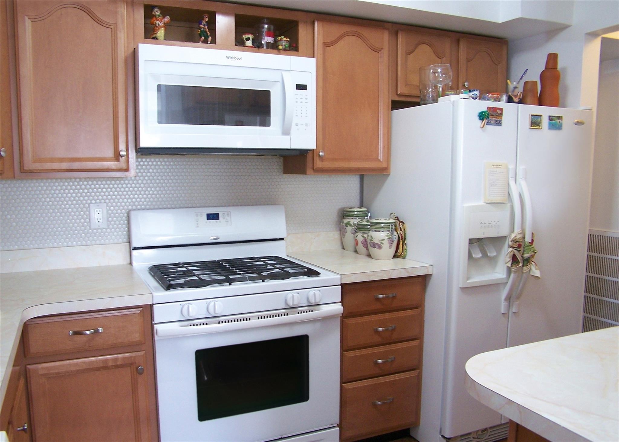51 Rocky Point Yaphank Road, Unit 5 Rocky Point, NY 11778 - Photo 7 of 17 Kitchen with white appliances, light countertops, decorative backsplash, and brown cabinetry