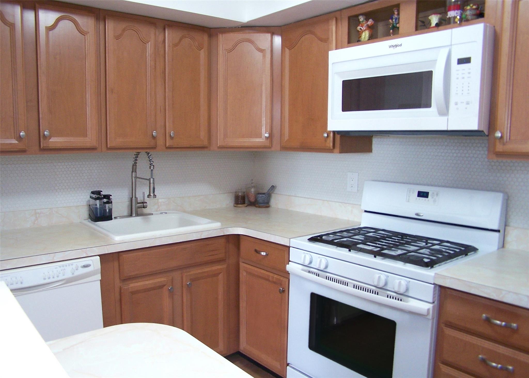 51 Rocky Point Yaphank Road, Unit 5 Rocky Point, NY 11778 - Photo 8 of 17 Kitchen with white appliances, a sink, light countertops, and brown cabinets