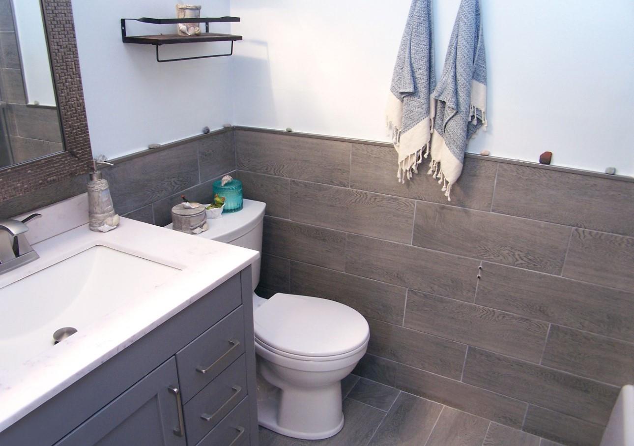 51 Rocky Point Yaphank Road, Unit 5 Rocky Point, NY 11778 - Photo 9 of 17 Bathroom featuring toilet, tile walls, vanity, a wainscoted wall, and wood finished floors