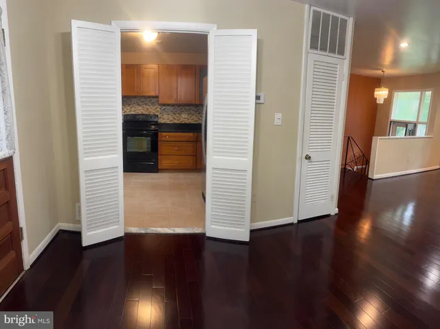 a view of a hallway with wooden floor and a bathroom