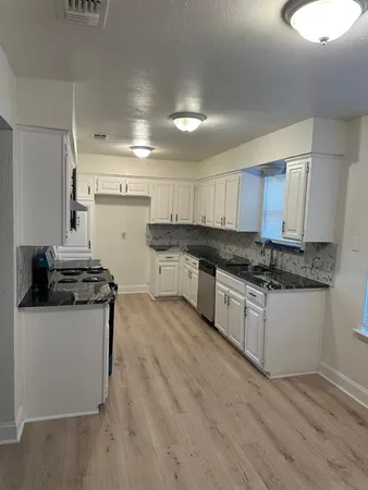 a kitchen with granite countertop a sink and a stove top oven