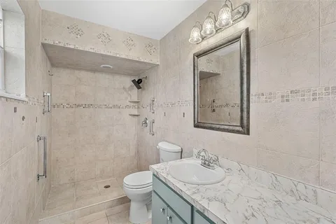 a bathroom with a granite countertop sink toilet and shower