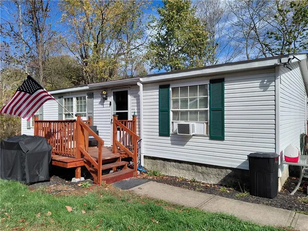 a view of a small house with a bed chairs and wooden fence