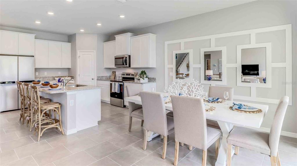 2337 Rikkola Lane Wesley Chapel, FL 33543 - Photo 5 of 17 a kitchen with stainless steel appliances kitchen island granite countertop a table chairs and a refrigerator