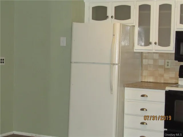 a view of a refrigerator in kitchen with white cabinets