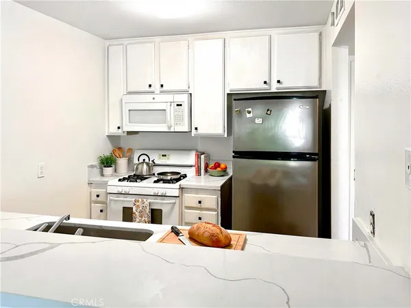 a kitchen with stainless steel appliances a stove refrigerator and white cabinets