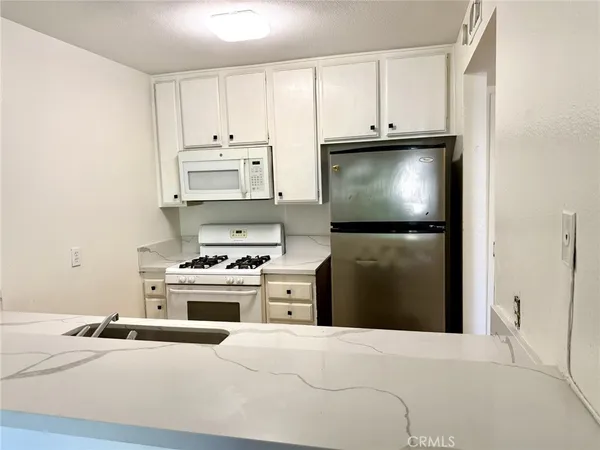 a kitchen with stainless steel appliances white cabinets and stove top oven