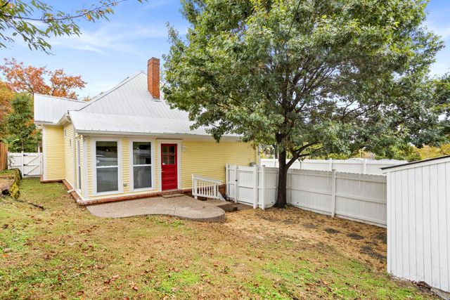 a view of a white house and a yard with wooden fence
