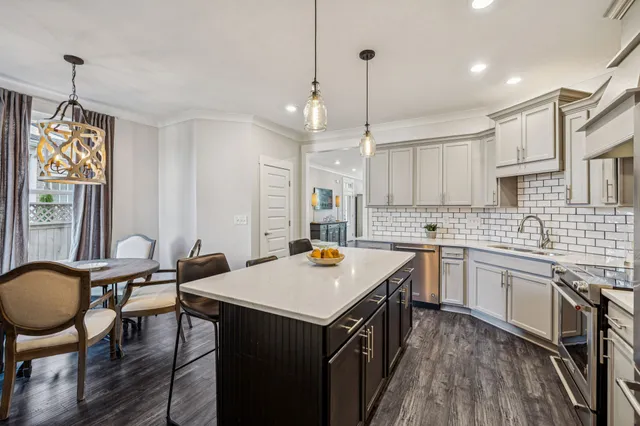 a kitchen with stainless steel appliances a refrigerator a sink a dining table and chairs