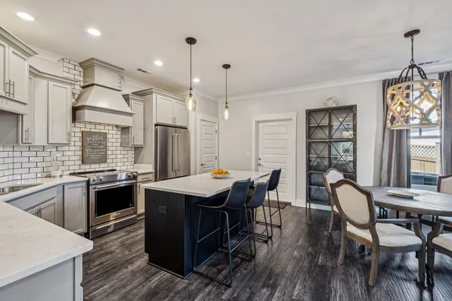 a kitchen with stainless steel appliances a sink dishwasher a refrigerator a stove and white cabinets with wooden floor