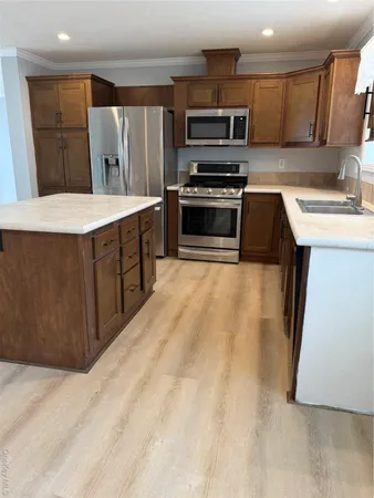 a kitchen with stainless steel appliances a sink a stove a microwave a sink a refrigerator and cabinets