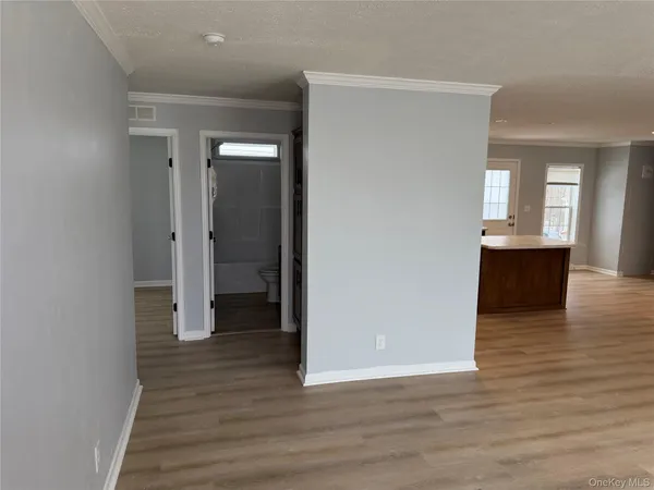 a view of a hallway with wooden floor and a kitchen